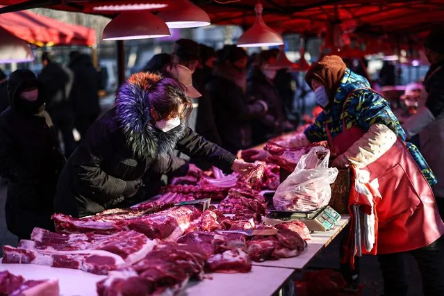 People shop for meat at a market in Shenyang in northeastern China's Liaoning province on January 12, 2024. (Photo by AFP Photo/China Stringer Network)