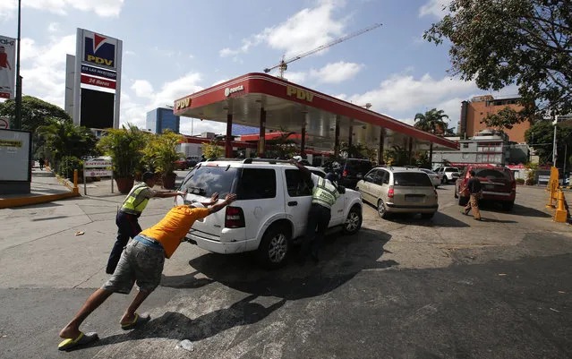 People push a car without fuel to one of the few gas stations that has its own electric generator during an electricity blackout in Caracas, Venezuela, Sunday, March 10, 2019. Power and communications outages continue to hit Venezuela, intensifying the hardship of a country paralyzed by economic and political crisis and heightening tension between the bitterly divided factions which accuse each other of being responsible for the collapse of the power grid. (Photo by Eduardo Verdugo/AP Photo)