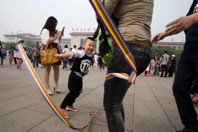 A child plays with a colored ribbon during a visit to Tiananmen Square in Beijing, Friday, May 1, 2015. (Photo by Ng Han Guan/AP Photo)