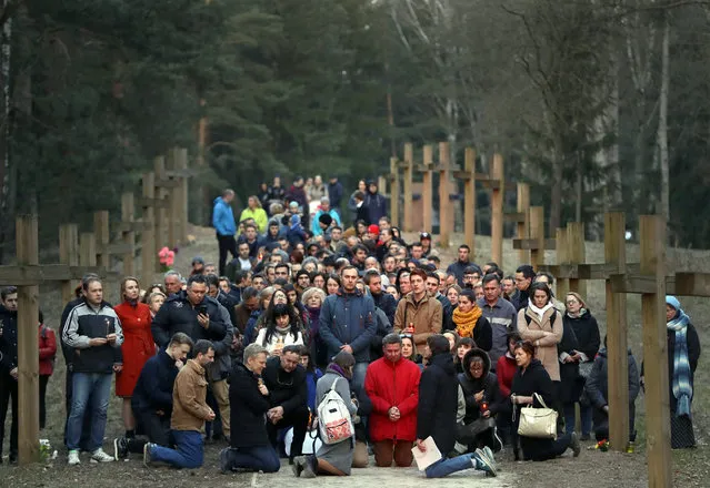 Local residents pray next to the line of wooden crosses marking the Soviet-era mass grave site in Kuropaty, in the Belarus capital Minsk, Thursday, April 4, 2019. Police in Belarus have arrested 15 demonstrators who were trying to prevent the removal of wooden crosses from a wooded area near the capital of Minsk where tens of thousands of people were executed under Soviet dictator Josef Stalin. (Photo by Sergei Grits/AP Photo)