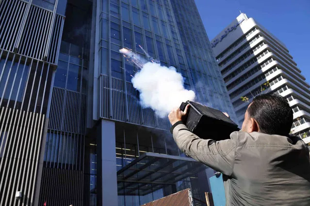 A depositor protester launches fireworks at a bank headquarters during a protest in Beirut, Lebanon, Friday, January 19, 2024. (Photo by Hussein Malla/AP Photo)