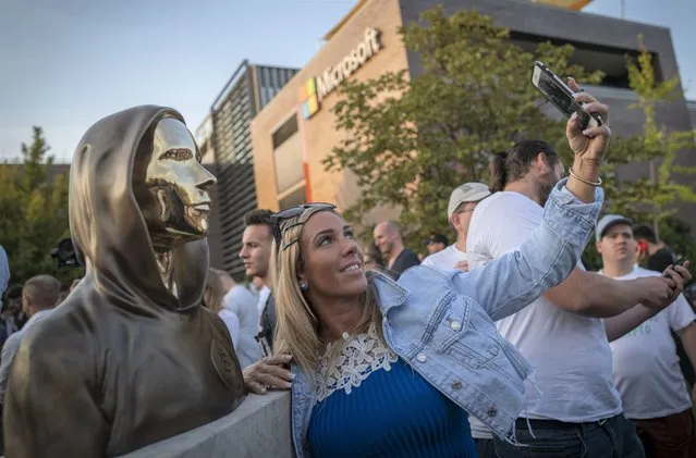 A woman takes a selfie with a newly unveiled statue of the mysterious developer of the Bitcoin digital currency in Budapest, Hungary, Thursday, September 16, 2021. A bronze statue was unveiled in Hungary’s capital on Thursday which its creators say is the first in the world to pay homage to the anonymous creator of the Bitcoin digital currency. Erected in a business park near the Danube River in Budapest, the bust sits atop a stone plinth engraved with the name of Satoshi Nakamoto, the pseudonym of the mysterious developer of Bitcoin whose true identity is unknown. (Photo by Bela Szandelszky/AP Photo)