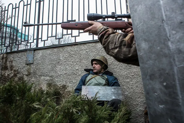 An anti-government protester aims a gun in the direction of suspected sniper fire near the Hotel Ukraine, on February 20, 2014. (Photo by Brendan Hoffman/Getty Images)