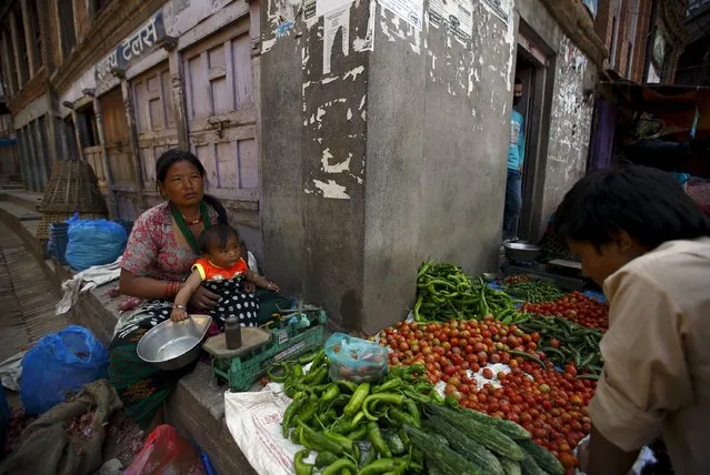 A woman from Sindhupalchok district holds her granddaughter as she sells vegetables along the streets of Bhaktapur after last week's earthquake 2 May 2015. According to the woman, her house was destroyed during the earthquake. (Photo by Navesh Chitrakar/Reuters)