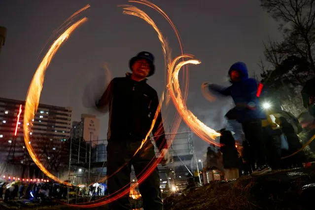 People whirl cans filled with burning wood chips during a celebration ahead of “Jeongwol Daeboreum” (Great Full Moon), the first full moon in the Korean lunar calendar in Seoul, South Korea, on February 24, 2024. (Photo by Kim Soo-Hyeon/Reuters)