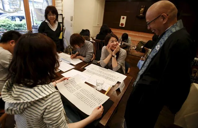 A woman speaks to Shokyo Miura, a Buddhist monk and one of the on-site priests, after tracing Buddhist sutras at Tera Cafe in Tokyo, Japan, April 1, 2016. (Photo by Yuya Shino/Reuters)