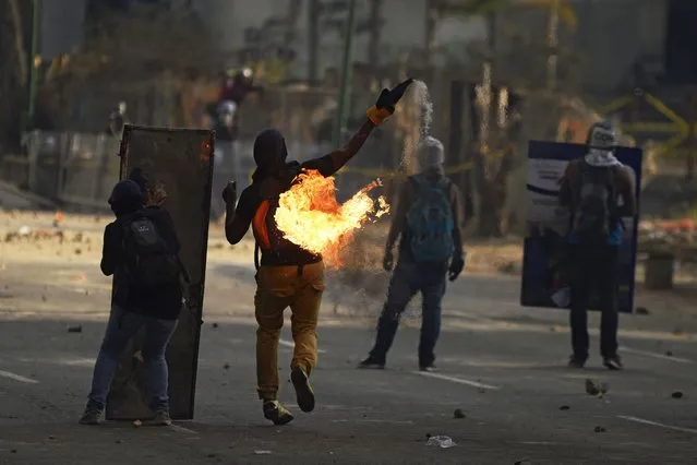 Demonstrators clash with the police during a protest against Venezuelan President Nicolas Maduro, in Caracas on March 16, 2014. Several hundreds of Venezuelans marched Sunday in Caracas against “Cuban interference”. Venezuela has seen almost daily anti-government demonstrations, with a death toll of 28, over violent crime, shortages of essential goods such as toilet paper, and soaring inflation, in the most serious challenge yet for Maduro since he succeeded late socialist-populist Hugo Chavez last year. (Photo by Juan Barreto/AFP Photo)