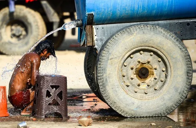 In this file photo taken on May 31, 2019, an Indian truck driver takes a bath using a water tanker as he tries to cool himself on a hot summer afternoon in Allahabad. Temperatures pushed towards 50 degrees Celsius (122 Fahrenheit) across much of India on June 1 as an unrelenting heatwave triggered warnings of water shortages and heat stroke. (Photo by Sanjay Kanojia/AFP Photo)
