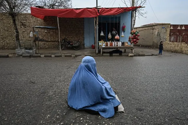 A woman wearing a burqa begs on a street in Mazar-i-Sharif on December 22, 2021. (Photo by Mohd Rasfan/AFP Photo)