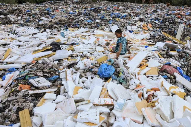 A child plays among rubbish at the Alue Lim landfill in Lhokseumawe, Aceh on January 13, 2022. (Photo by Azwar Ipank/AFP Photo)