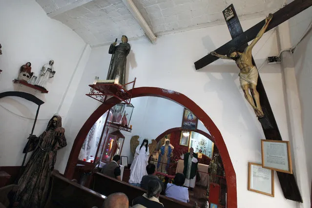 In this February 19, 2017 photo, Juan Carlos Avila Mercado leads a religious service, surrounded by images of local saints, Saint Death, Immaculate Conception, Saint Judas Thaddeus and the Virgin of Guadalupe, at Mercy Church in Mexico City. The Church located on the edge of the Tepito neighborhood is home to the cult of the Death Saint, or “La Santa Muerte” in Spanish, a female figure cloaked in black who carries a scythe, which the Roman Catholic Church rejects. (Photo by Marco Ugarte/AP Photo)