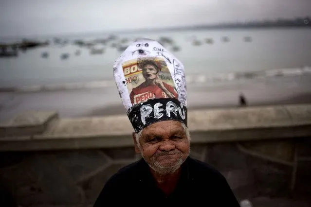 Carlos Humala poses for the picture wearing a makeshift hat resembling the Pope's, with a picture of soccer player Paolo Guerrero, during Saint Peter's day celebrations in Lima, Peru, Monday, June 29, 2015. During the feast day of the Catholic saint, who is the patron saint of fishermen, coastal communities pay homage to St. Peter, whose statue is paraded to the sea and petitions are made to keep their vessels and all who work on them safe. (Photo by Rodrigo Abd/AP Photo)