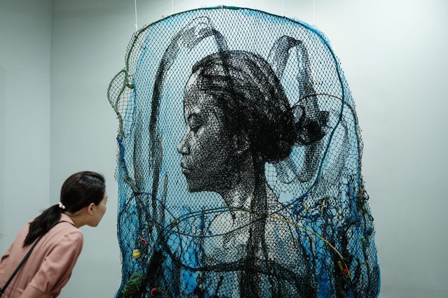 A visitor looks at Indonesian artist Iwan Yusuf's artwork titled “Infinity” made of used and new fishing nets during the Jakarta Art Gardens art fair in Jakarta on April 28, 2024. (Photo by Yasuyoshi Chiba/AFP Photo)