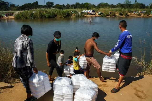 Refugees, who have fled a flare-up in fighting between the Myanmar army and insurgent groups and settled temporarily on the Moei River Bank, receive aid from Thailand on the Thai-Myanmar border, in Mae Sot, Thailand, January 7, 2022. (Photo by Athit Perawongmetha/Reuters)