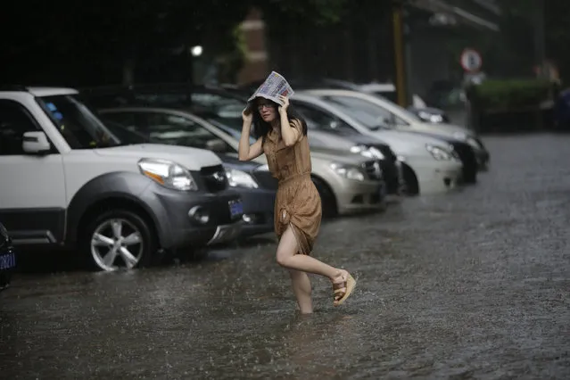 A woman walks on the flooded street from a heavy thunderstorm in Shanghai, China, Friday, September 13, 2013. Sudden and heavy thunderstorm hit the city in the afternoon Shanghai and caused the flood with rain water over many streets. (Photo by Eugene Hoshiko/AP Photo)