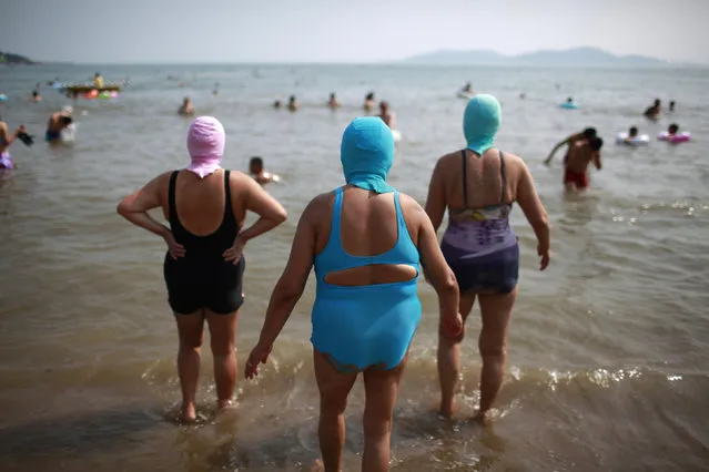Women, wearing nylon masks, walk towards the sea during their visit to a beach in Qingdao, Shandong province July 6, 2012. (Photo by Aly Song/Reuters)