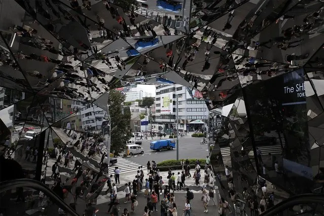 Shoppers are reflected in mirrors of a mall in the district of Shibuya in Tokyo, Japan, Monday, October 7, 2019. Shibuya is the most energetic district in Tokyo, offering countless restaurants, shops and entertainments. (Photo by Christophe Ena/AP Photo)