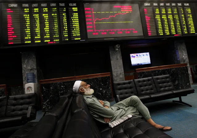 A man takes a nap on a couch under an electronic board displaying share prices during trading session at the Karachi Stock Exchange April 2, 2014. (Photo by Akhtar Soomro/Reuters)