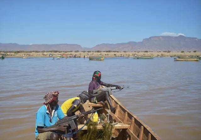 Armed fishermen from Kenya's Turkana county return from a fishing expedition aboard a boat on March 24, 2017 near Lowarengak, on the western shores of Lake Turkana, northern Kenya. Lake Turkana has gradually receded in recent years leading to diminished fish stocks and territory that has forced traditional communities on the eastern as well as the northern shores, in Ethiopia, of the world's largest permanent desert lake within undesired proximity of each other regularly ending in deadly clashes. (Photo by Tony Karumba/AFP Photo)