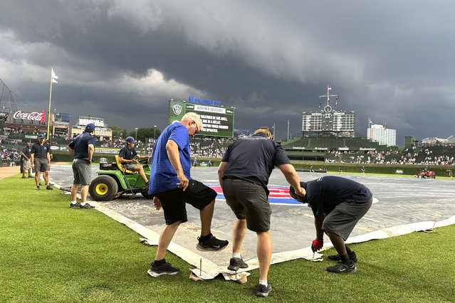 Members of the Wrigley Field ground crew prepare the field during a rain delay as storm clouds descend over the stadium before a baseball game between the Chicago Cubs and the Milwaukee Brewers on Tuesday, July 23, 2024, in Chicago. (Photo by Charles Rex Arbogast/AP Photo)