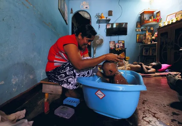 A woman comforts a baby with water in a tub during the power cut as many parts of the country currently face long power cuts, as currency shortage makes fuel scarce, in Colombo, Sri Lanka on March 31, 2022. (Photo by Dinuka Liyanawatte/Reuters)
