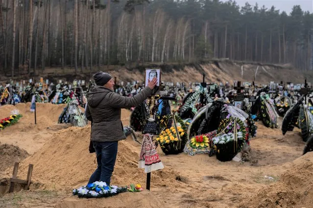 Alla Prohonenko, 53, touches a photo of her father Volodymyr Prohonenko during his funeral in Irpin, cemetery on the outskirts of Kyiv, on Thursday, April 21, 2022. Proponenko died during the Russian occupation. (Photo by Petros Giannakouris/AP Photo)