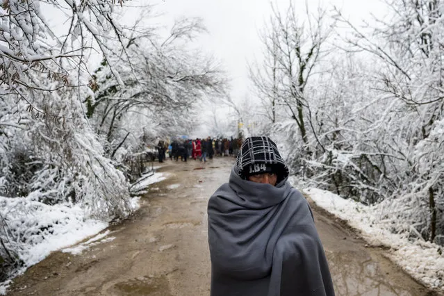 A migrant walks covered with a blanket during a winter day covered by snow at the Vucjak refugee camp outside Bihac, northwestern Bosnia and Herzegovina, 03 December 2019. (Photo by Jean-Christophe Bott/EPA/EFE)