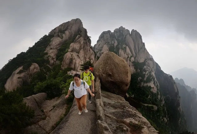 This photo taken on June 16, 2014 shows Chinese tourists hiking on Lotus Peak which is the most revered of the Huangshan (Yellow Mountains) peaks at the park in Anhui Province. The UNESCO World Heritage Site is one of China's major tourist destinations and has been a source of inspiration to Chinese painters, writers and poets for thousands of years. (Photo by Mark Ralston/AFP Photo)