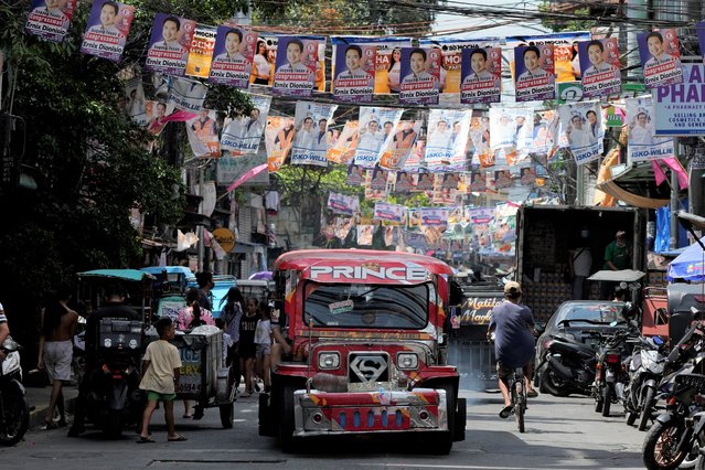 A passenger jeepney passes campaign posters outside a polling center in Manila, Philippines on May 6, 2022. The winner of May 9, Monday's vote will inherit a sagging economy, poverty and deep divisions, as well as calls to prosecute outgoing leader Rodrigo Duterte for thousands of deaths as part of a crackdown on illegal drugs. (Photo by Aaron Favila/AP Photo)