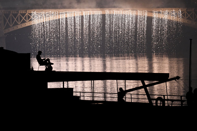 A man sits in a chair on top of a tourist ship to watch the fireworks exploding over the river Danube from Margaret bridge close to the parliament building on August 20 2024 as part of celebrations marking the Hungary's National Day, in Budapest. Hungary marks the 1,024th anniversary of the foundation of the Hungarian state, established by the first king of Hungary, Stephen I. (Photo by Attila Kisbenedek/AFP Photo)