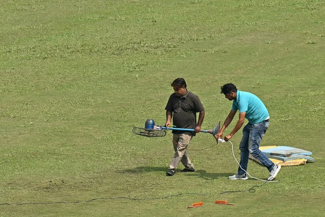 Groundsmen use a fan to dry a patch of wet outfield before the start of the one-off Test cricket match between Afghanistan and New Zealand at the Shaheed Vijay Singh Pathik Sports Complex in Greater Noida on September 10, 2024. The one-off Test between Afghanistan and New Zealand near New Delhi was delayed again on September 10, with the toss still yet to take place, after overnight rain. (Photo by Money Sharma/AFP Photo)