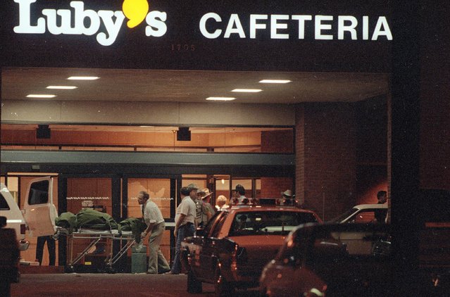 Officials remove bodies from Luby's Cafeteria off Interstate I-90 at Killeen, Bell County, Texas, on Wednesday night, October 16, 1991. The gunman, George Hennard, crashed his pickup truck through the window of the restaurant at lunchtime and opened fire, killing 23 people and wounding 20 others, before killing himself. (Photo by Ron Heflin/AP Photo)