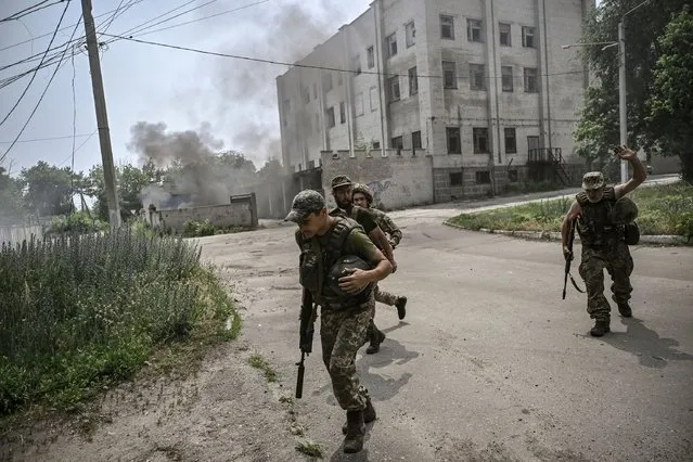 Ukrainian servicemen run for cover during an artillery duel between Ukrainian and Russian troops in the city of Lysychansk, eastern Ukrainian region of Donbas, on June 11, 2022. (Photo by Aris Messinis/AFP Photo)