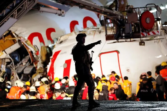A security personnel in tactical gear gestures near the Pegasus Airlines Boeing 737-86J plane, that overran the runway during landing and crashed, at Istanbul's Sabiha Gokcen airport, February 5, 2020. The plane carrying 171 passengers from the Aegean port city of Izmir split into three after landing in rough weather. Officials said no-one had lost their lives in the accident, but dozens of people were injured. (Photo by Murad Sezer/Reuters)