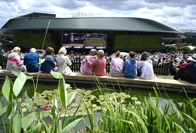 Spectators watch first round matches on a giant screen outside Court No.1 at the Wimbledon Championships in Wimbledon, Britain, 28 June 2022. (Photo by Andy Rain/EPA/EFE)
