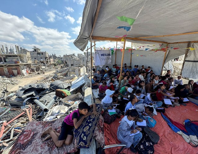 Palestinian students attend a class in a tent set up on the ruins of the house of teacher Israa Abu Mustafa, as war disrupts a new school year, amid the Israel-Hamas conflict, in Khan Younis, in the southern Gaza Strip, on October 10, 2024. (Photo by Mohammed Salem/Reuters)