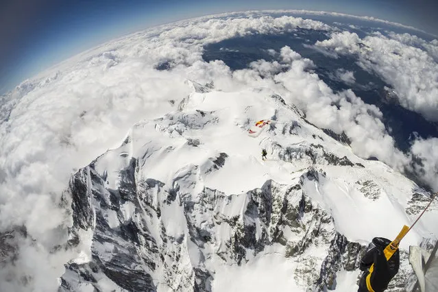 Fred Fugen and Vincent Reffet seen jumping at 33,000 feet (10 km) above the Mont Blanc, French Alps on May 31, 2014. Fearless skydivers jump from an altitude of 10,000 meters above the largest mountain in Europe. Frederic Fugen, 34, and Vincent Reffet, 29, leapt from a plane in the freezing skies above Mont-Blanc in the French Alps. The jump is from such a height the pictures show the curvature of the earth. (Photo by Dominique Daher/Barcroft Media)