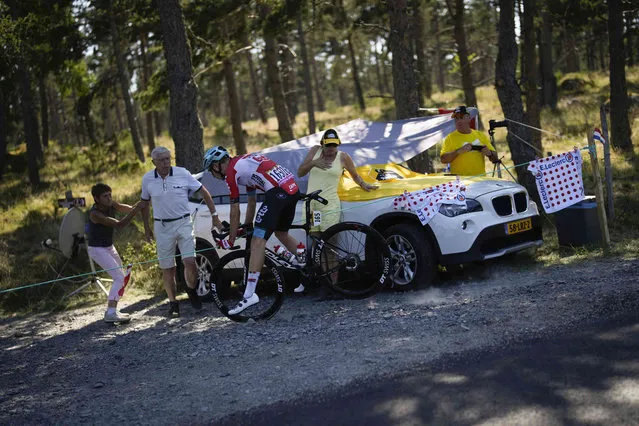 Denmark's Andreas Kron goes off the road with a flat rear tire almost crashing into the car of cycling fans from The Netherlands during the fourteenth stage of the Tour de France cycling race over 192.5 kilometers (119.6 miles) with start in Saint-Etienne and finish in Mende, France, Saturday, July 16, 2022. (Photo by Daniel Cole/AP Photo)