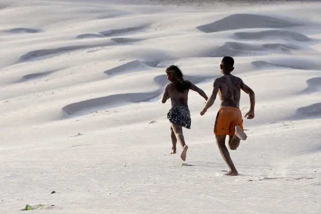 Youths run along sand dunes during the peak of the summer vacation season on Atalaia beach in Salinopolis, Para state, July 27, 2014. (Photo by Paulo Santos/Reuters)