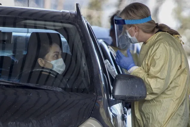 An Alberta Health Services employee speaks with a motorist at a drive-thru coronavirus testing facility in Calgary, Alberta, Friday, March 27, 2020. (Photo by Jeff McIntosh/The Canadian Press via AP Photo)