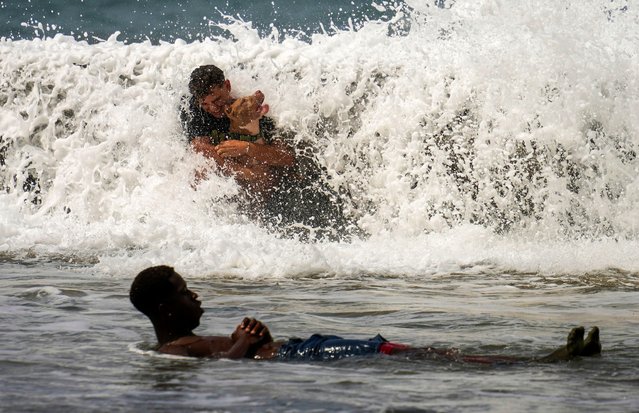 A man and his dog lean against the Malecon seawall as they play in the water crashing over it onto the sidewalk brought by Hurricane Milton passing through the Gulf of Mexico, in Havana, Cuba, Wednesday, October 9, 2024. (Photo by Ramon Espinosa/AP Photo)