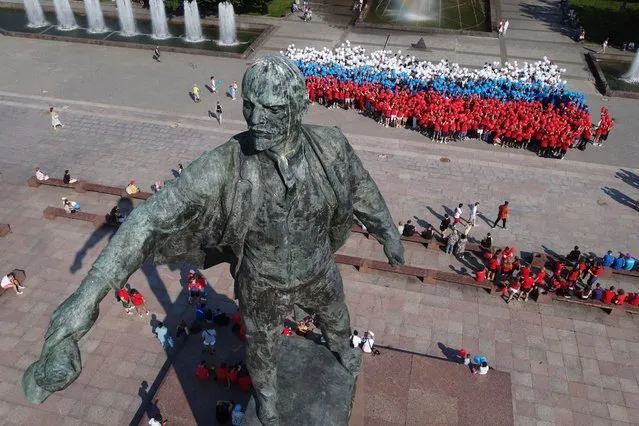 Members of pro-government youth clubs stand in the shape of the image of Russia on the map holding balloons in the colours of the Russian flag near a statue of Soviet Union founder Vladimir Lenin during preparations for the celebration of the Day of the Russian National Flag, which will be held on August 22, in St. Petersburg, Russia, Friday, August 19, 2022. (Photo by Dmitri Lovetsky/AP Photo)