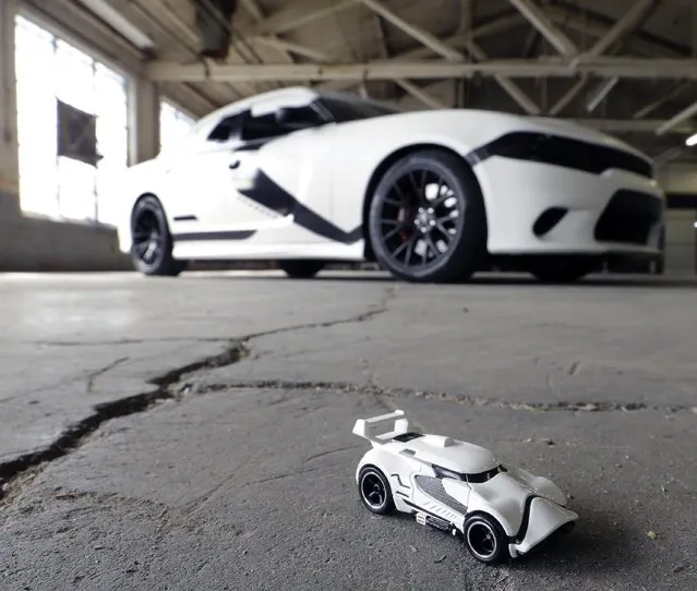 A Star Wars decorated Dodge Charger modeled after a First Order Stormtrooper Car is seen near a First Order Stormtrooper Car toy in a warehouse Thursday, September 3, 2015, in Paterson, N.J. Inspired by the film Star Wars, Hot Wheels is taking over New York City on “Force Friday” September 4  with a fleet of Stormtrooper vehicles. (Photo by Mel Evans/AP Photo)