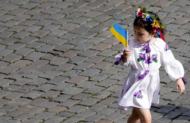 A young girl walks with a Ukrainian flag during an event for Ukrainian Independence Day in the historical Grand Place of Brussels, Wednesday, August 24, 2022. European leaders are pledging unwavering support for Ukraine as the war-torn country marks its Independence Day. The commemorations Wednesday coincide with the six-month milestone of Russia's invasion. (Photo by Virginia Mayo/AP Photo)