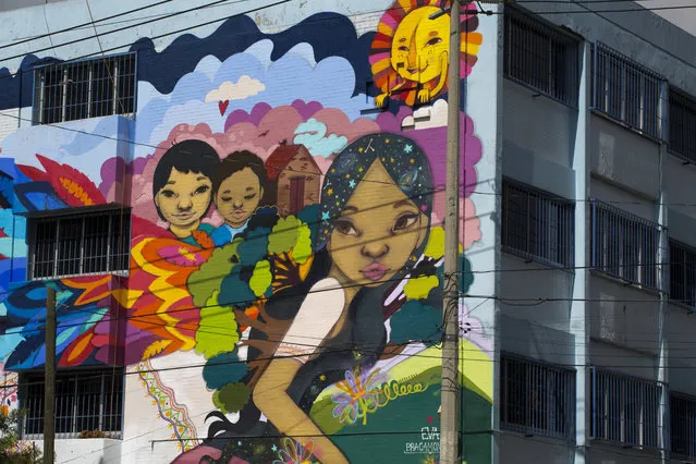 In this August 13, 2017 photo, a woman fleeing with her children and her home on her bank is seen on a street mural being designed and painted by asylum seekers along with Mexican artist Eva Bracamontes in Mexico City. Mexico has hosted large numbers of Central American refugees in the past, especially during the region’s civil wars of the 1970s and 1980s. But in recent years it has been better known as a perilous passageway to the United States in which northbound migrants often have been preyed upon by criminal gangs who rape, rob, kidnap and kill. (Photo by Rebecca Blackwell/AP Photo)
