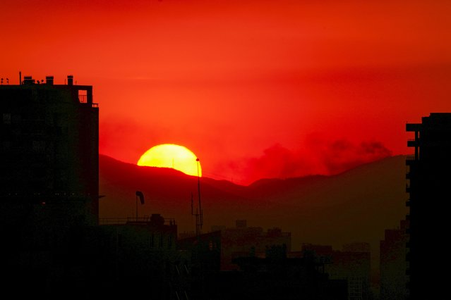 The sun sets in Santiago, Chile, Friday, December 20, 2024, as a forest fires burns on the outskirts of the capital. (Photo by Esteban Felix/AP Photo)