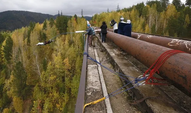 A member of the “Exit Point” amateur rope-jumping group jumps from a 44-metre high (144-ft) waterpipe bridge in the Siberian Taiga area outside Krasnoyarsk, September 13, 2015. (Photo by Ilya Naymushin/Reuters)