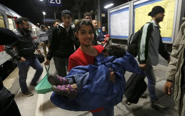 A migrant girl of Syria carries her brother as they arrive at the main railway station in Dortmund, Germany September 13, 2015. (Photo by Ina Fassbender/Reuters)