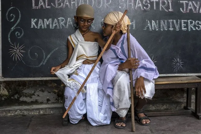 School children dressed as iconic independence leader Mahatma Gandhi sit on a bench after taking part in an event to mark his birth anniversary in Mumbai, India, Sunday, October 2, 2022. (Photo by Rafiq Maqbool/AP Photo)