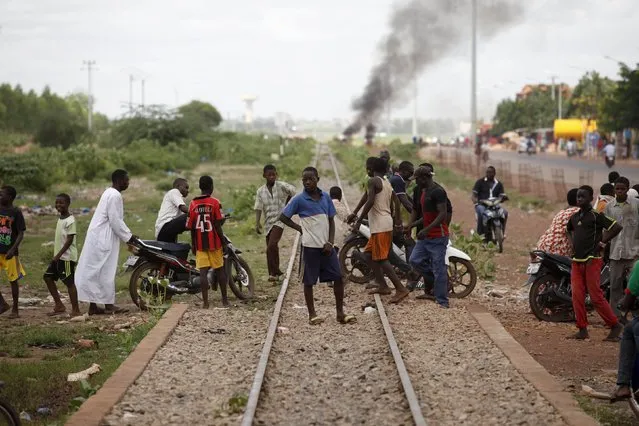 People cross a railway next to a burning barricade (not pictured) in Ouagadougou, Burkina Faso, September 19, 2015. (Photo by Joe Penney/Reuters)